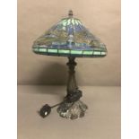 A blue and turquoise stained glass Tiffany style lamp with dragon fly detail