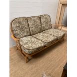 An Ercol sitting room suite consisting of three arm chairs, a foot stool and a three seater sofa (