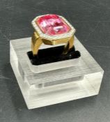 A Fashion ring in gold marked 18 with central pink stone and white stone surround. Approximate Total