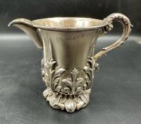 A Victorian silver embossed cream jug with floral design, indistinct hallmarks.