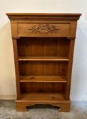 A pine three shelf bookcase with fluted sides and floral detail to top (H115cm W70cm D27cm)