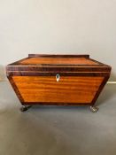 A sarcophagus tea caddy with inlay and brass lion paw feet. Inside has been relined in felt and hand