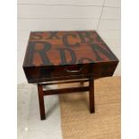 A table on cross stretcher stand opening up to a desk with writing slope and drawers with alphabet