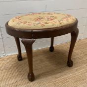 An oval mahogany dressing stool upholstered in a floral pattern on ball and claw feet AF