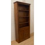 A three shelf stained pine book case with two door cupboard under (H200cm W90cm D32cm)