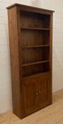A three shelf stained pine book case with two door cupboard under (H200cm W90cm D32cm)