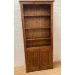 A three shelf stained pine book case with two door cupboard under (H200cm W90cm D32cm)