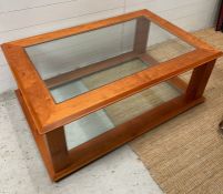 A cherry wood coffee table with glass panel to top and base (H47cm W120cm D80cm)