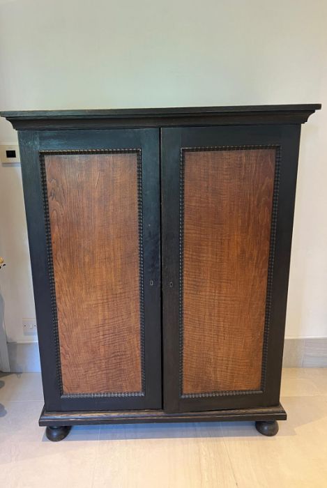 A painted cupboard with panelled doors opening to hanging rail and pigeon holes