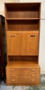 A Mid Century G Plan three drawer sideboard with drop down drinks cabinet and two shelves above (