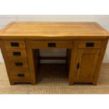 A pine knee hole desk with drawers to one side and cupboard to other with wrought iron handles (