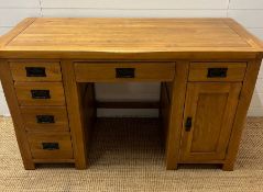 A pine knee hole desk with drawers to one side and cupboard to other with wrought iron handles (