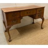 A knee hole desk on scrolling legs finishing on claw and ball feet (H79cm W55cm D122cm)