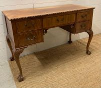 A knee hole desk on scrolling legs finishing on claw and ball feet (H79cm W55cm D122cm)