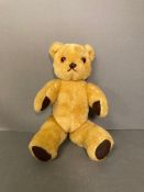 A vintage teddy bear with jointed arms and legs.