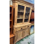 An antique pine glazed dresser, the glazed top hinged doors opening to shelves and a cupboard base