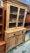 An antique pine glazed dresser, the glazed top hinged doors opening to shelves and a cupboard base