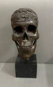 A decorative bronze sculpture of a skull on plinth