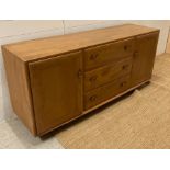 An Ercol three drawer, two cupboard sideboard on castors (H70cm W44cm D156cm)