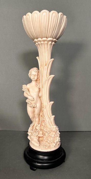 A sculptural figure of a girl leaning against a tree with floral detail