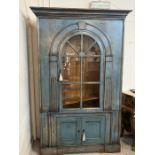 A colonial style wall cabinet with glazed hinged doors opening to adjustable shelving. With keys.