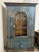 A colonial style wall cabinet with glazed hinged doors opening to adjustable shelving. With keys.