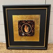 A framed decorative tile in gold and black with central anatomical heart