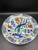 A 12 nik pottery plate, the circular dish decorated with floral design of rusty reds and cobalt