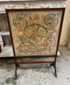 A mahogany framed fire screen on splayed feet with floral tapestry insert