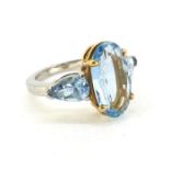 In platinum, with the centre aquamarine claw set with yellow gold a 3 stone ring. Total weight of