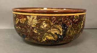 A Lambeth Doulton stoneware Faience bowl with grapes on vine leaves, signed OT and dated 1876 (