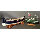 Two wooden painted scale model boats, a rowing boat on trailer and a fishing trawler on plinth