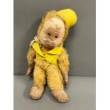 A vintage monkey with jointed arms and legs, leather hands and feet wearing a yellow felt hat and