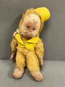 A vintage monkey with jointed arms and legs, leather hands and feet wearing a yellow felt hat and