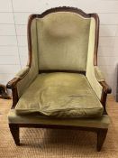 An Easy wingback armchair with carved shaped back, down swept winged sides, finishing with scrolling