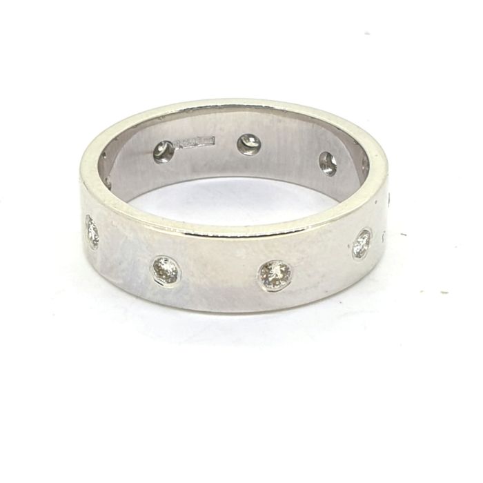 A hallmarked 6mm wide band ring set with nine equally spaced diamonds.Ring size O1/2, white gold