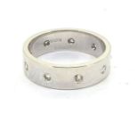 A hallmarked 6mm wide band ring set with nine equally spaced diamonds.Ring size O1/2, white gold