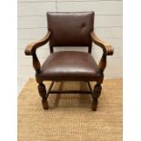 An oak brown leather studded upholstered open armchair on carved legs