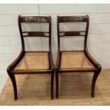 A pair of cane seated regency style chairs with brass inlay.