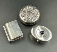 Three silver pill boxes, one in the shape of a book.
