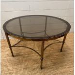 A circular Mid Century smoked glass coffee/stick table on reeded brass support on pentagram