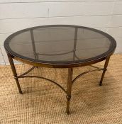 A circular Mid Century smoked glass coffee/stick table on reeded brass support on pentagram