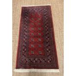 A red wool ground rug (72cm x 142cm) by Muskabad (Belgium)