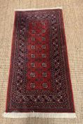 A red wool ground rug (72cm x 142cm) by Muskabad (Belgium)