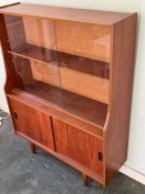 A Mid Century teak display unit, sliding doors to top on tapering legs (H118cm W91cm D29cm)