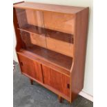 A Mid Century teak display unit, sliding doors to top on tapering legs (H118cm W91cm D29cm)