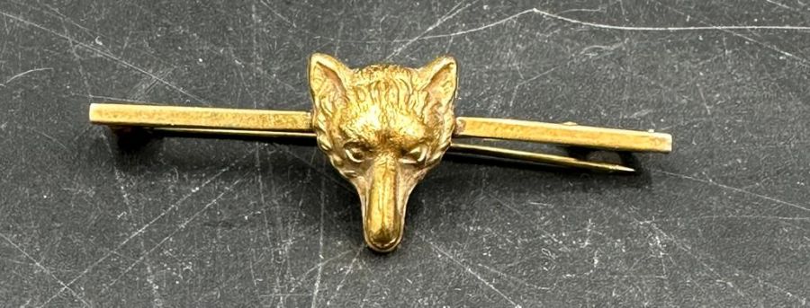 Two gold metal brooches one of three swallows the other of a foxes head.