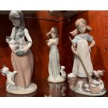 Three Lladro ladies, two with pig tails holding cats