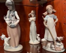 Three Lladro ladies, two with pig tails holding cats