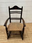 An oak child's rocking chair with reeded seat on inlaid to back